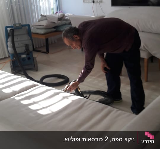אדם מנקה ספה עם מכונת ניקוי מקצועית